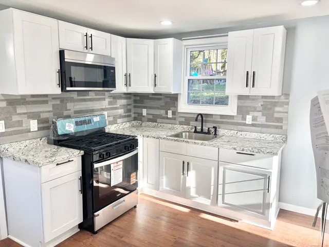 a kitchen with granite countertop a stove a sink and a microwave