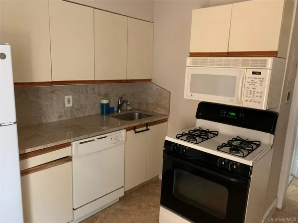 a kitchen with white cabinets and appliances