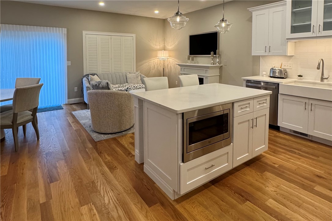 25 Franklin Road, Unit 1 East Greenwich, RI 02818 - Photo 5 of 38 At the heart of the kitchen sits a beautiful quartz-topped island with seating for two, ideal for morning coffee or evening conversation. The built-in under-counter microwave keeps the design seamless and the space uncluttered.