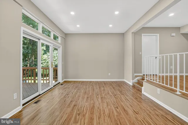 a view of an empty room with wooden floor and windows