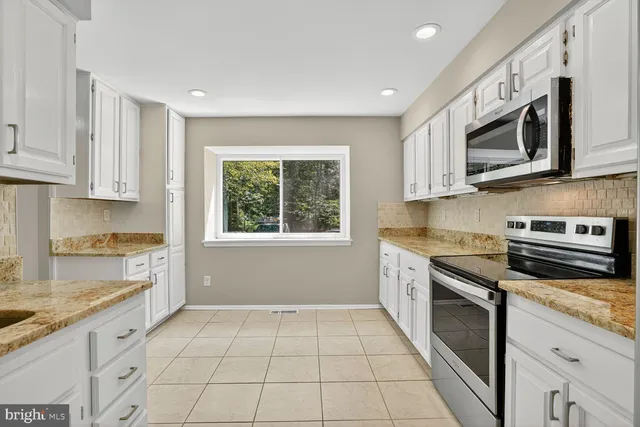 a kitchen with stainless steel appliances granite countertop white cabinets granite counter tops and a window