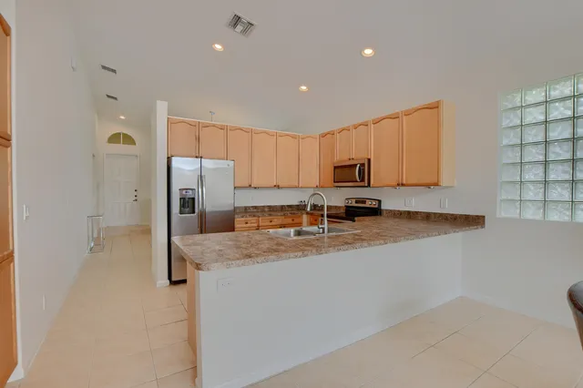 a kitchen with stainless steel appliances granite countertop a refrigerator a stove a sink a microwave a oven and white cabinets with wooden floor