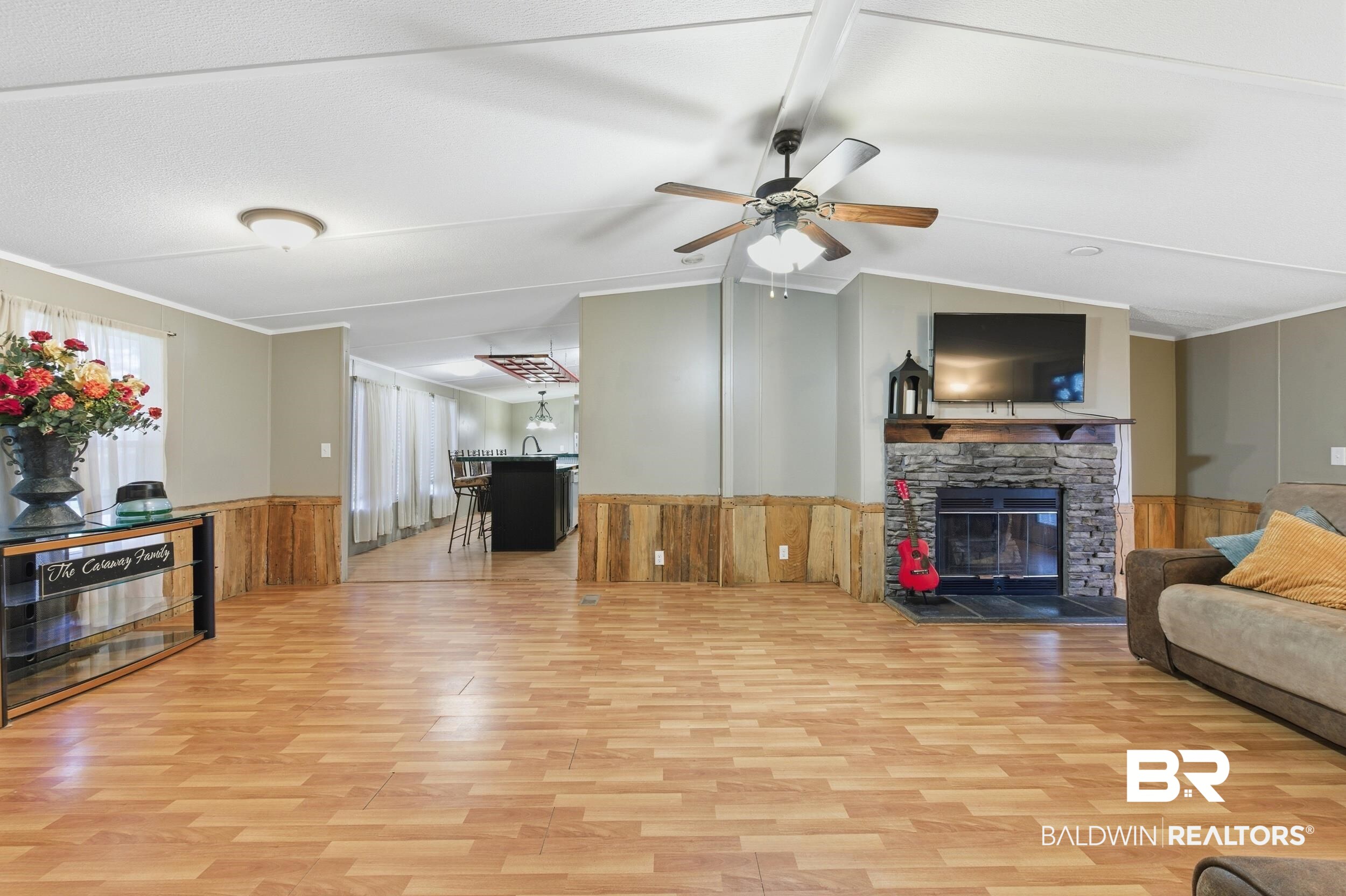926 Tumbling Lane Atmore, AL 36502 - Photo 16 of 56 Spacious living area featuring wood-finish flooring, a stone-clad fireplace with a wood mantle, and a ceiling fan