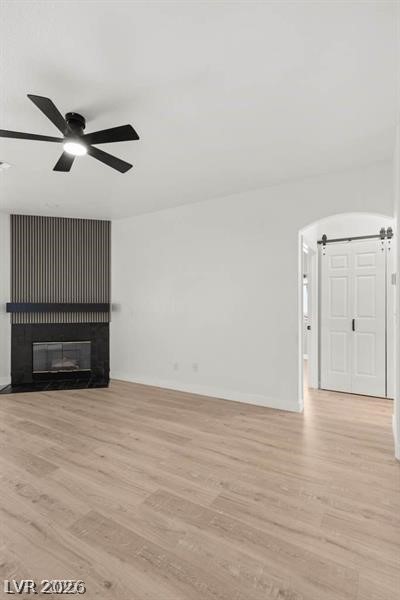 3320 South Fort Apache Road, Unit 125 Las Vegas, NV 89117 - Photo 5 of 26 A striking fireplace with a dark surround anchors this open living space, featuring rich wood flooring and a modern ceiling fan.