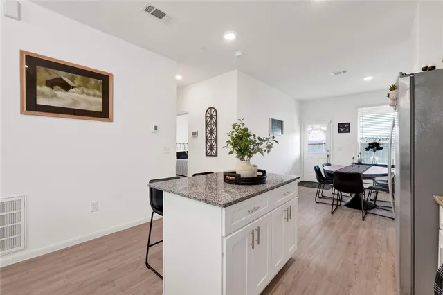 a living room with stainless steel appliances granite countertop furniture wooden floor and a view of kitchen
