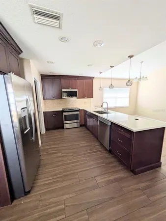 a kitchen with stainless steel appliances a sink a stove a refrigerator and cabinets