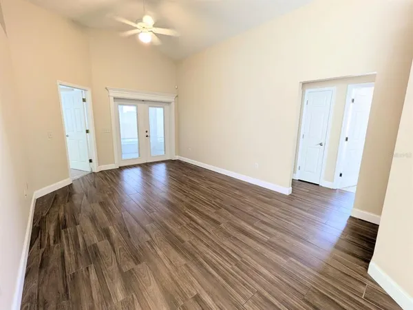 a view of an empty room with wooden floor and a ceiling fan