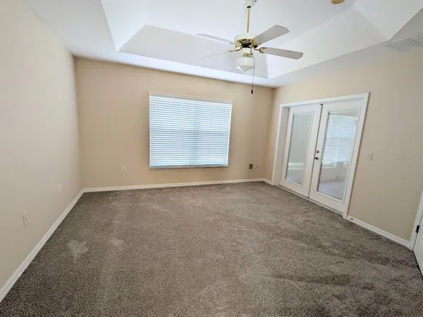 an empty room with windows and fan