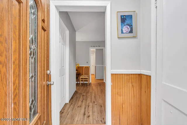 a view of a hallway with wooden floor and a bathroom