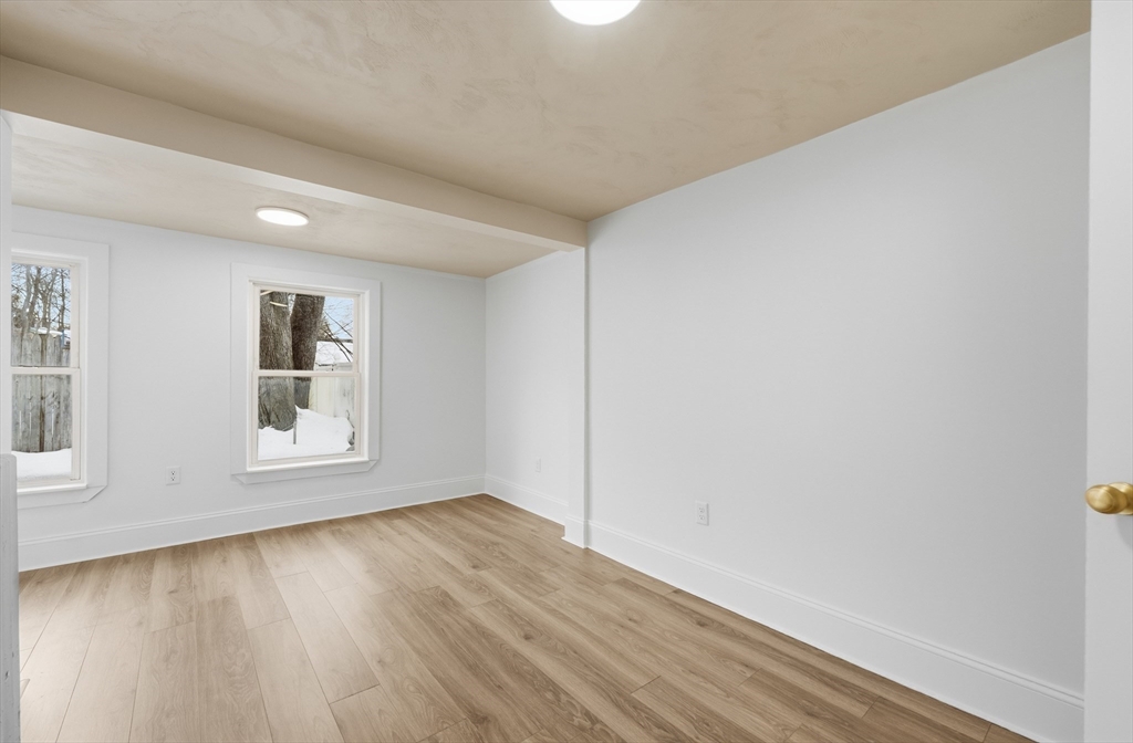22 Douglas Avenue, Unit 1 Maynard, MA 01754 - Photo 6 of 19 an empty room with wooden floor and windows