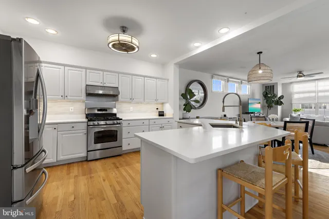 a kitchen with stainless steel appliances a sink a stove a refrigerator cabinets and living room view