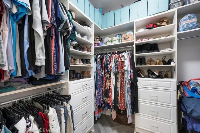 a view of walk in closet with clothes and shoes