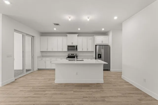 a view of kitchen with granite countertop stainless steel appliances refrigerator sink and cabinets