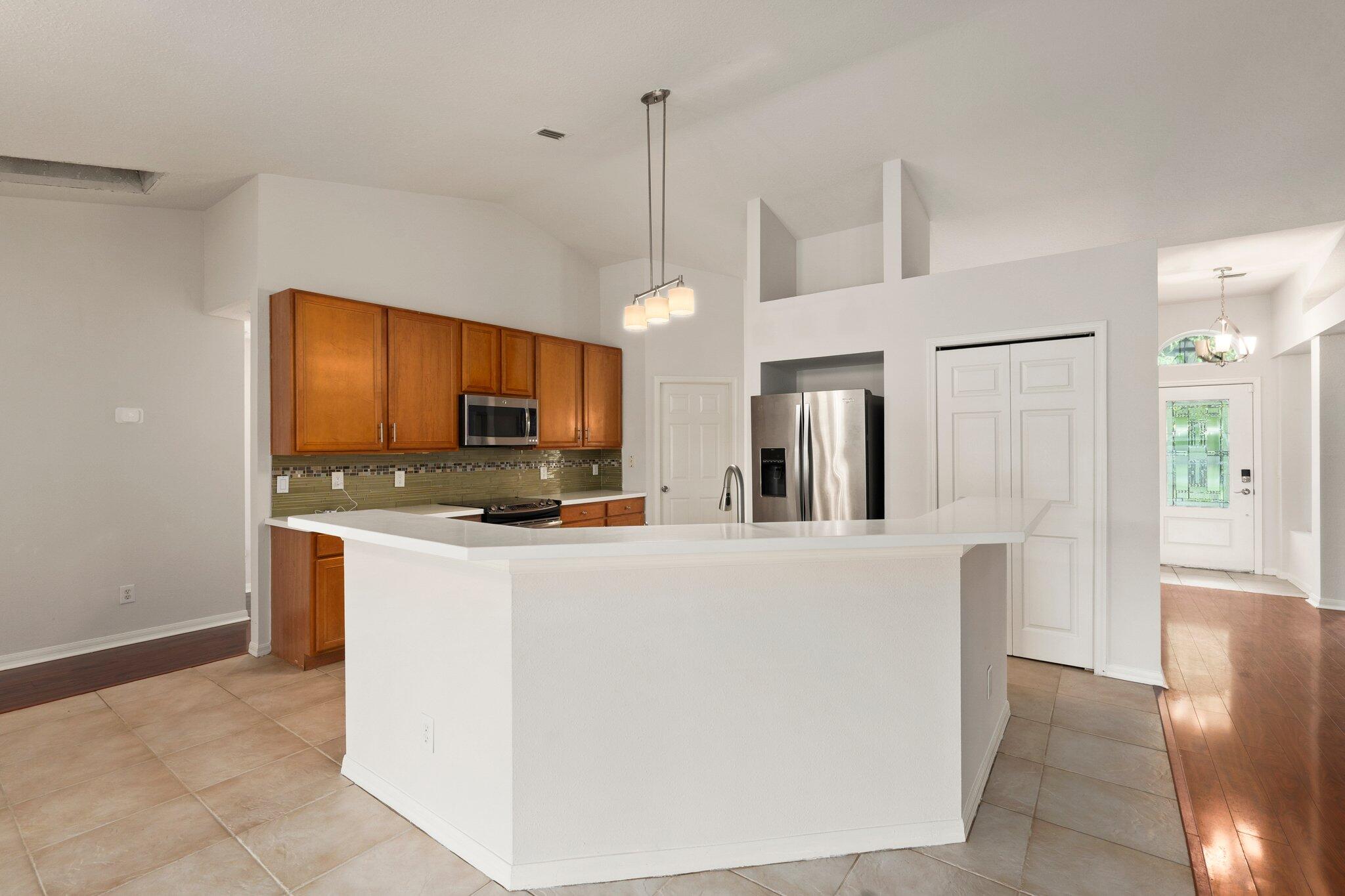 1901 Southwest Diamond Street Port St. Lucie, FL 34953 - Photo 12 of 42 a living room with stainless steel appliances kitchen island a flat screen tv and a refrigerator