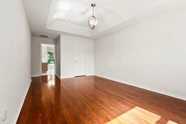 a view of an empty room with wooden floor and window