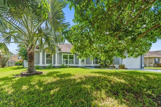 a view of a house with a big yard and large trees