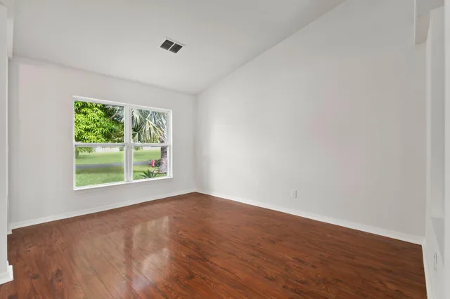 a view of an empty room with wooden floor and a window