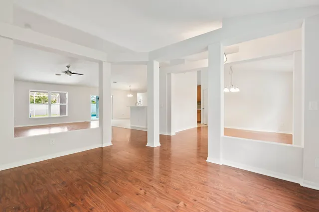 a view of an empty room with window and wooden floor