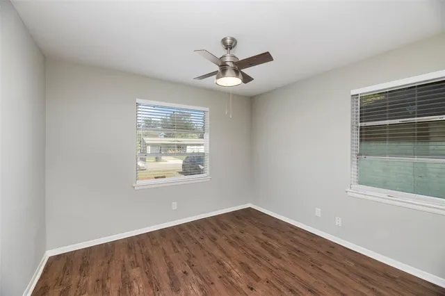 an empty room that has a window and wooden floor
