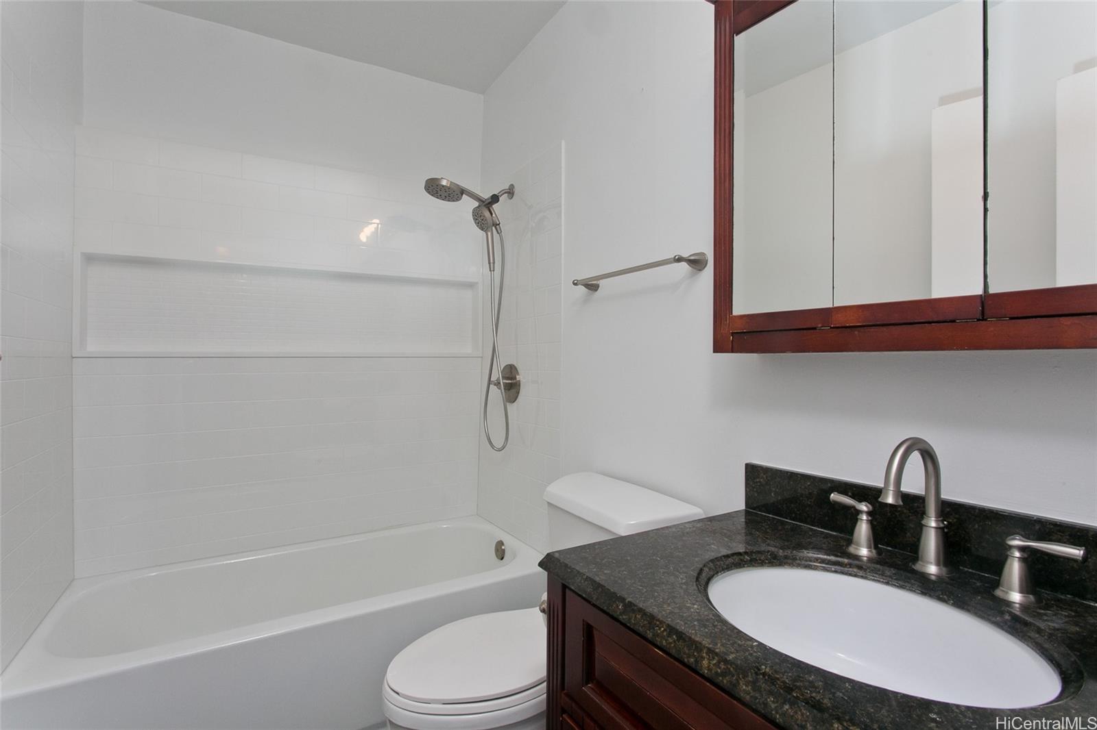 3045 Ala Napuaa Place, Unit 306 Honolulu, HI 96818 - Photo 9 of 15 a bathroom with a granite countertop sink toilet a mirror and shower