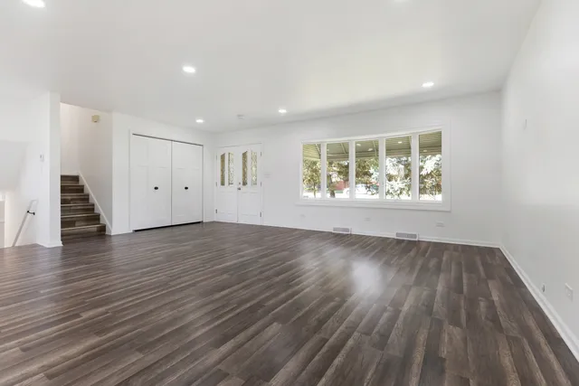 an empty room with wooden floor and windows