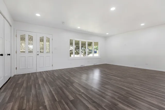 an empty room with wooden floor and windows