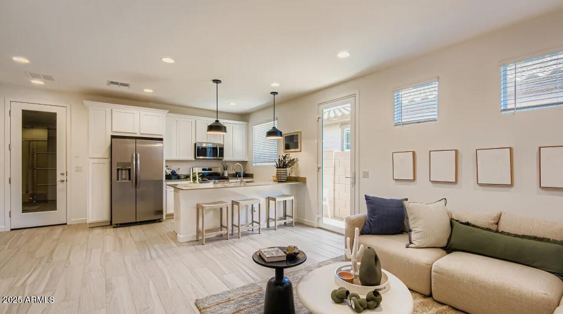9540 West Flower Street Phoenix, AZ 85392 - Photo 11 of 22 a kitchen with stainless steel appliances kitchen island granite countertop a refrigerator a stove a oven a dining table and chairs with wooden floor