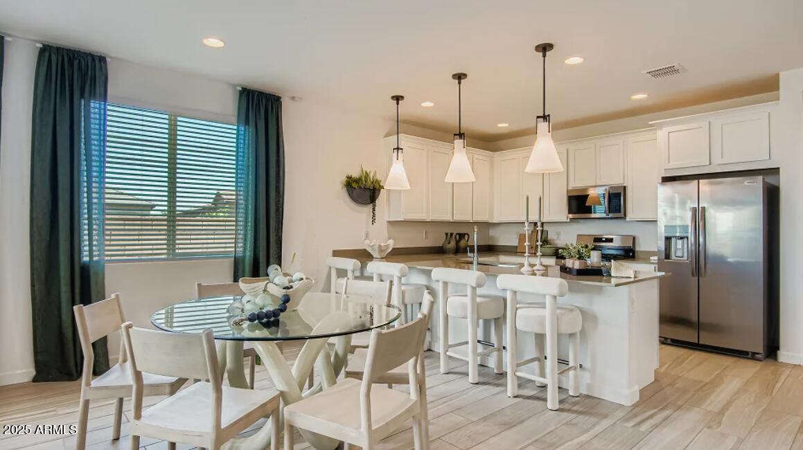 9540 West Flower Street Phoenix, AZ 85392 - Photo 4 of 22 a kitchen with stainless steel appliances kitchen island granite countertop a dining table chairs and a refrigerator