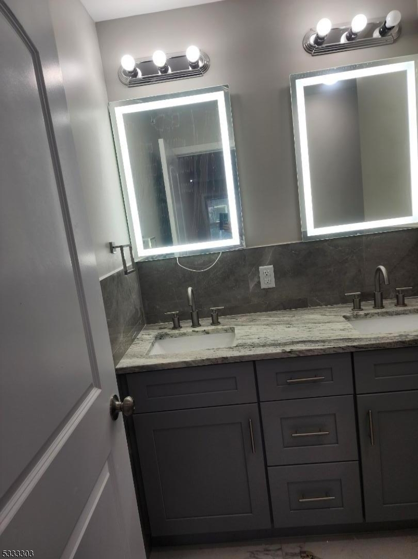 a bathroom with double vanity and a mirror