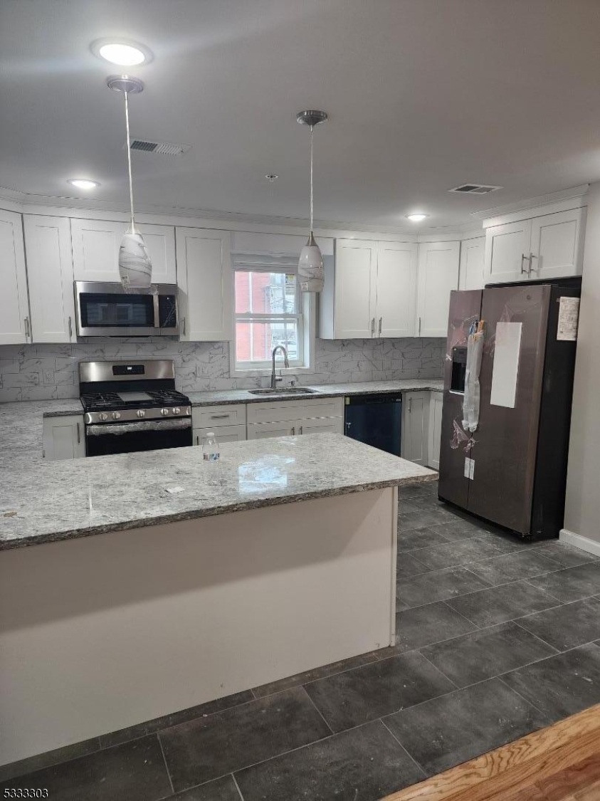 20 Garibaldi Avenue Newark, NJ 07114 - Photo 9 of 12 a kitchen with stainless steel appliances granite countertop a stove a refrigerator a sink a microwave and white cabinets