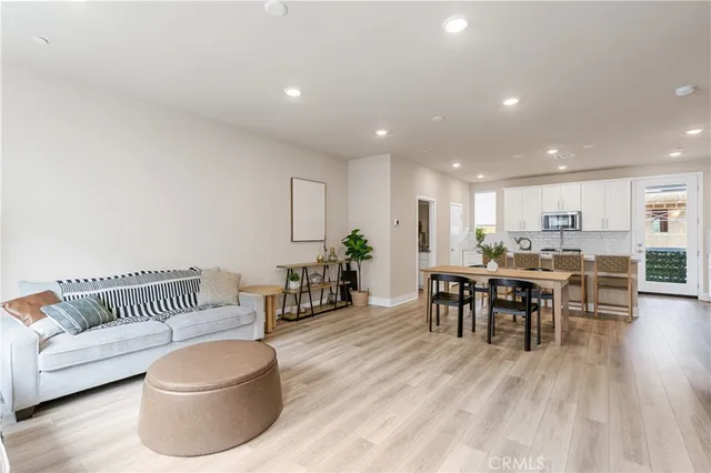 a living room with furniture and a dining table with wooden floor