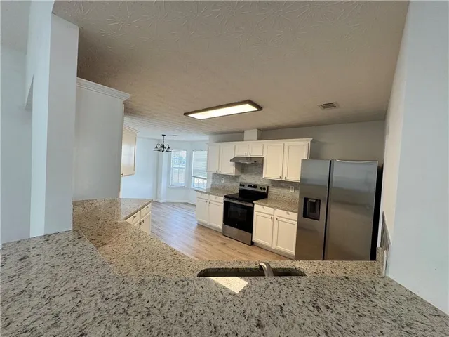 a kitchen with stainless steel appliances granite countertop a refrigerator stove top oven and sink