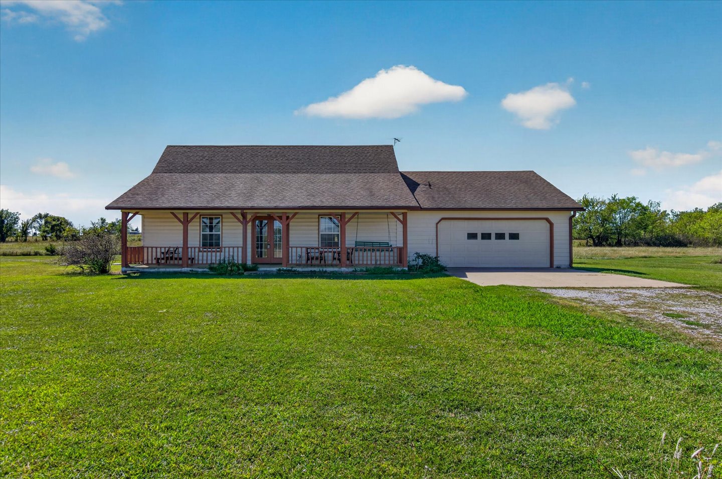 26115 4157th Road Nowata, OK 74048 - Photo 1 of 36 Charming ranch-style residence featuring a covered front porch with decorative columns, a spacious attached two-car garage, and expansive grounds with manicured lawn and mature landscaping