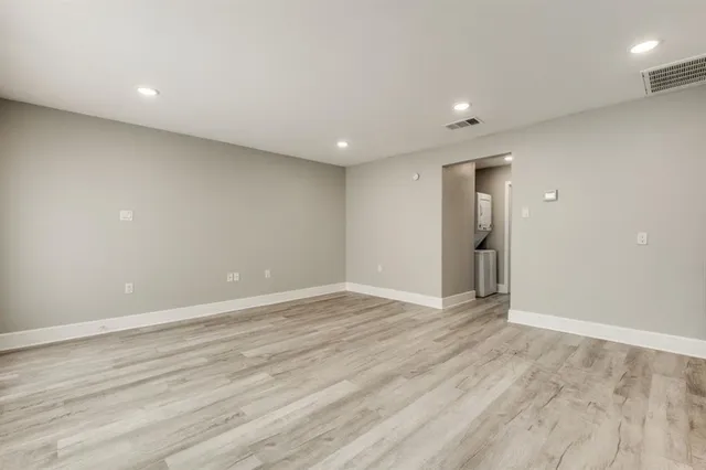 an empty room with wooden floor and natural light