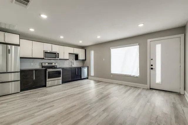 a large kitchen with stainless steel appliances granite countertop a stove a sink and a refrigerator