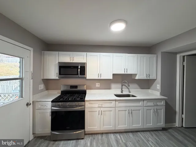 a kitchen with granite countertop a sink stainless steel appliances and cabinets