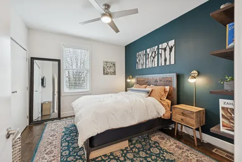 a bedroom with a bed a dresser and potted plant