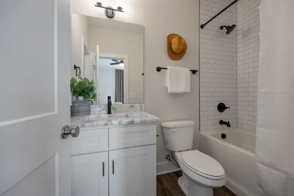 a bathroom with a granite countertop sink a toilet a mirror and shower