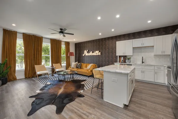 a living room with furniture a large window and wooden floors