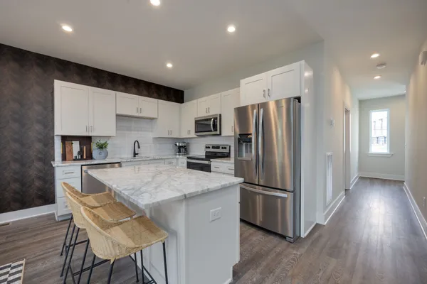 a kitchen with granite countertop a refrigerator and a stove top oven