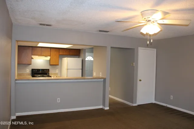 a view of a room with a chandelier fan and wooden floor