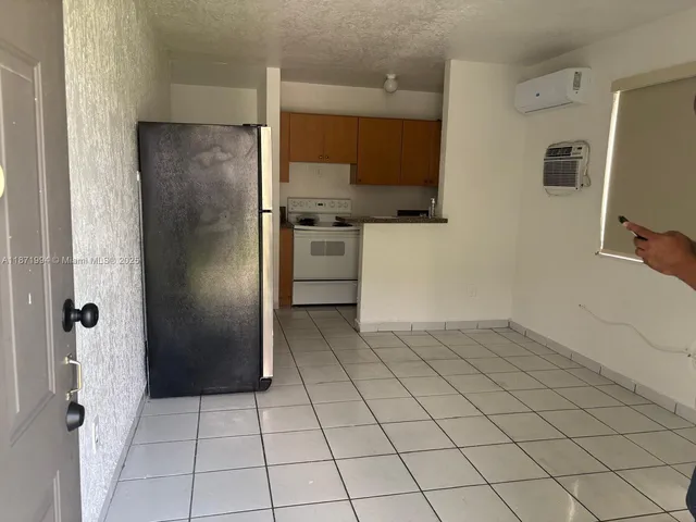 a view of a refrigerator in kitchen and an empty room