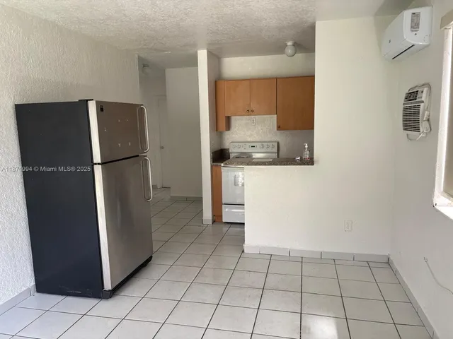 a kitchen with a refrigerator a stove top oven and cabinets