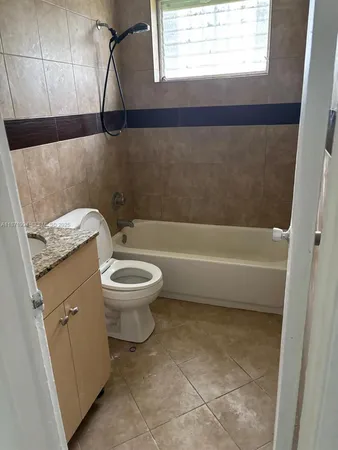 a bathroom with a granite countertop toilet a sink and a bathtub