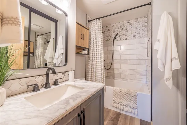 a bathroom with a granite countertop sink a mirror and shower