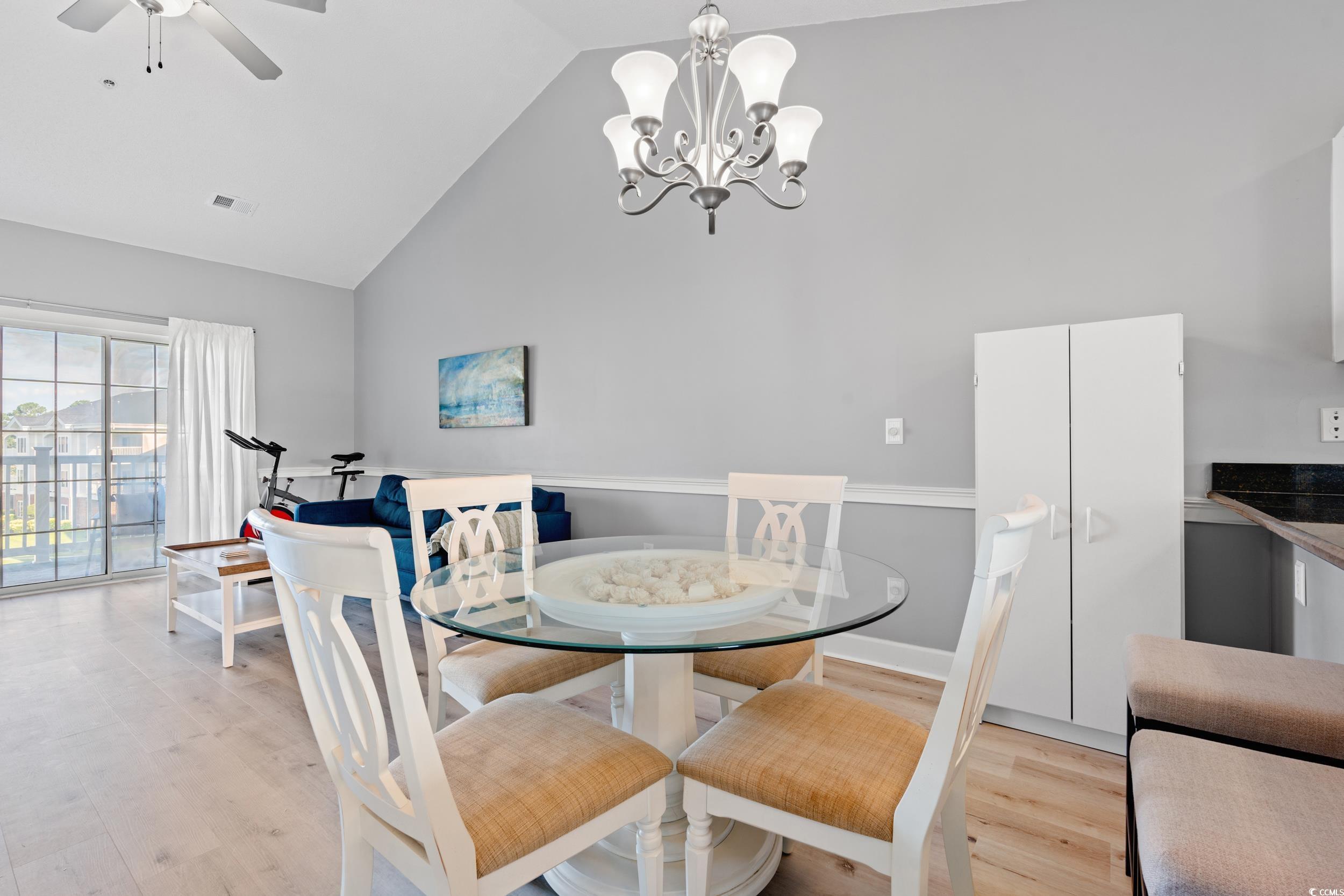 4864 Carnation Circle, Unit 304 Myrtle Beach, SC 29577 - Photo 11 of 36 Dining area featuring high vaulted ceiling, light wood-style flooring, a chandelier, and a ceiling fan