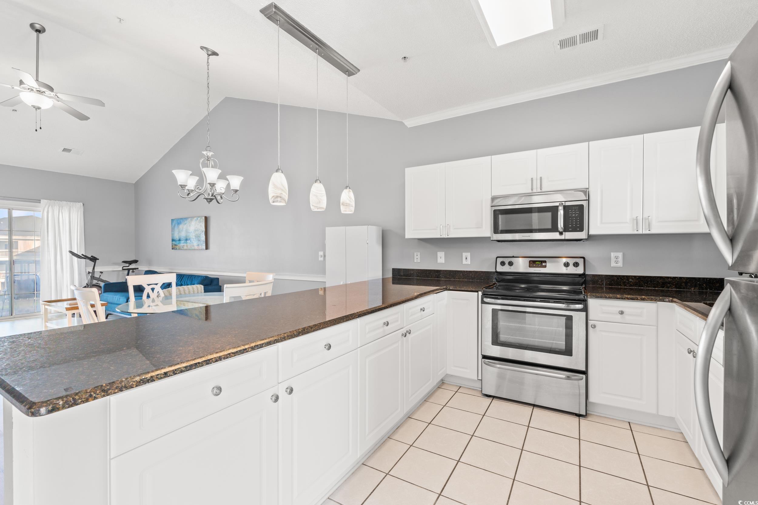 4864 Carnation Circle, Unit 304 Myrtle Beach, SC 29577 - Photo 13 of 36 Kitchen with stainless steel appliances, white cabinetry, hanging light fixtures, a peninsula, and vaulted ceiling