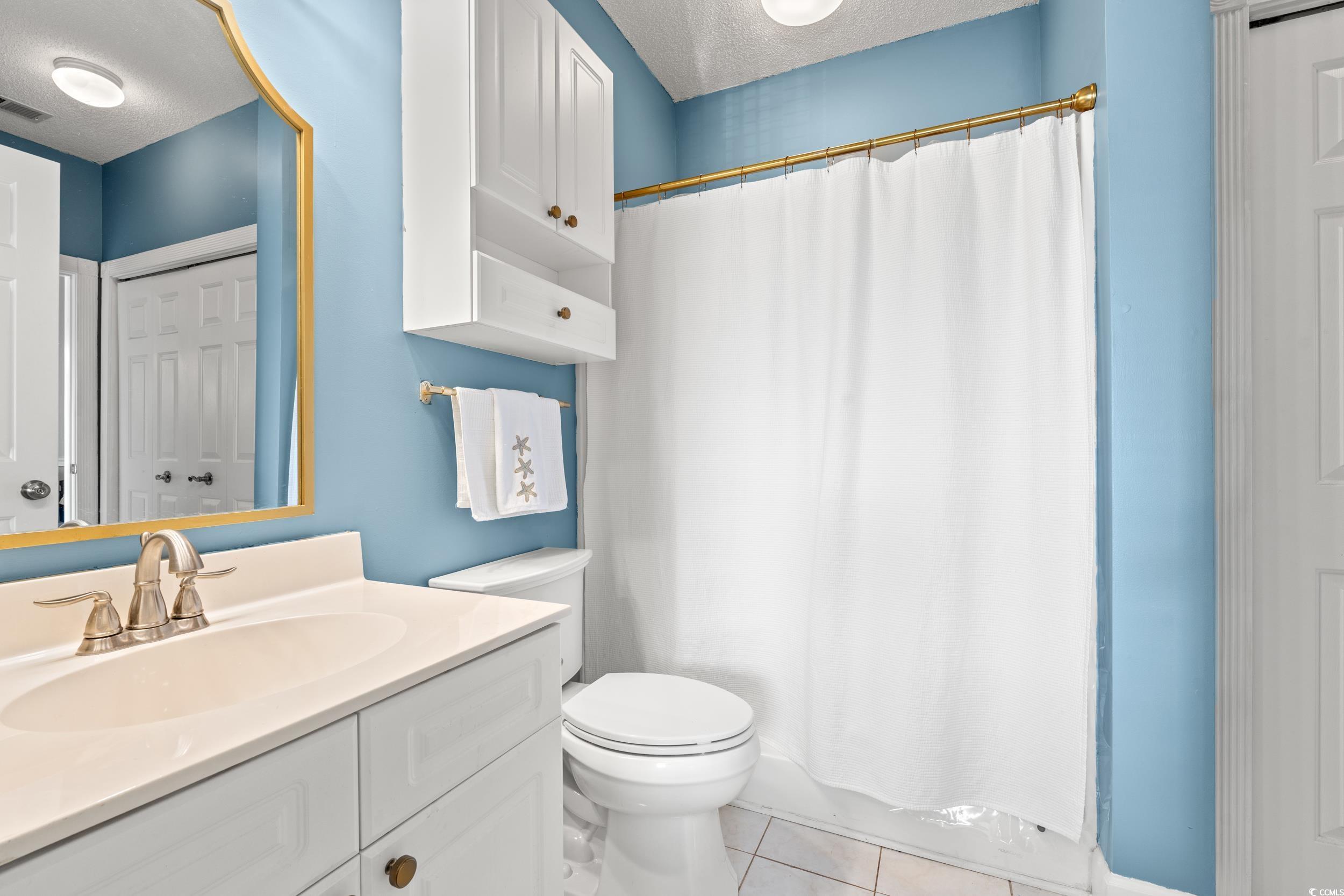 4864 Carnation Circle, Unit 304 Myrtle Beach, SC 29577 - Photo 21 of 36 Full bath featuring a textured ceiling, light tile patterned flooring, vanity, and curtained shower