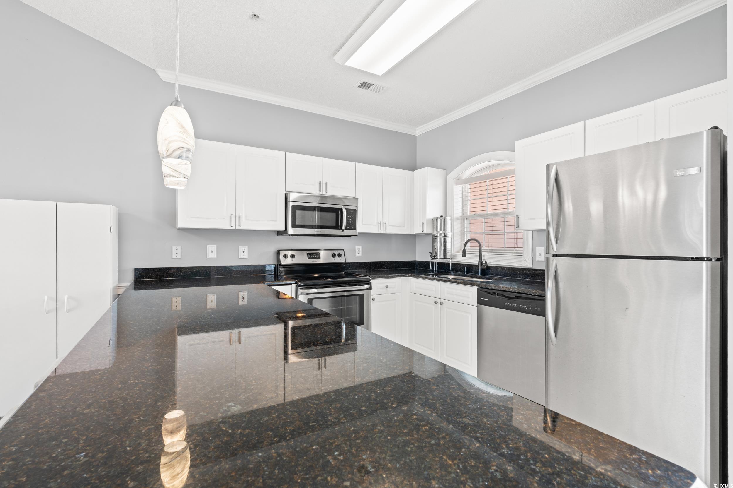 4864 Carnation Circle, Unit 304 Myrtle Beach, SC 29577 - Photo 3 of 36 Kitchen with appliances with stainless steel finishes, ornamental molding, decorative light fixtures, white cabinets, and dark stone countertops