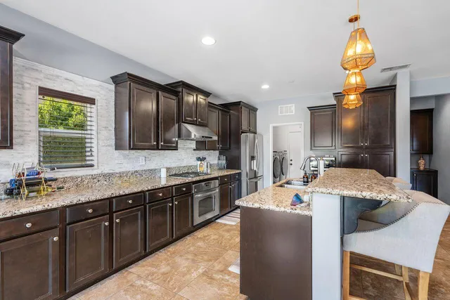 a kitchen with stainless steel appliances granite countertop a refrigerator stove and oven